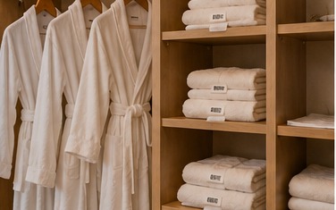 Tagged robes and towels organized on hotel storage shelving